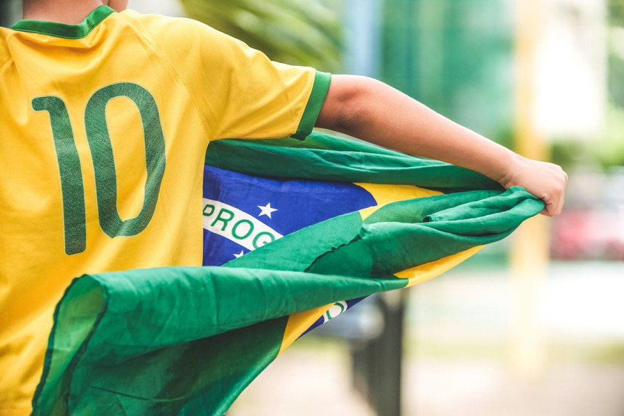 Boy wearing Brazil jersey with Brazil flag in hand