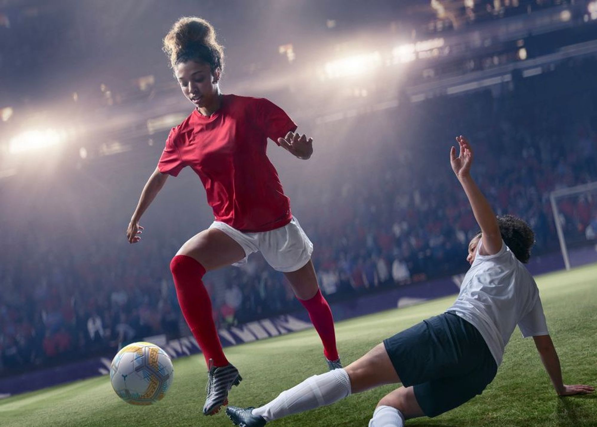 Female Footballer Jumping Over Tackle