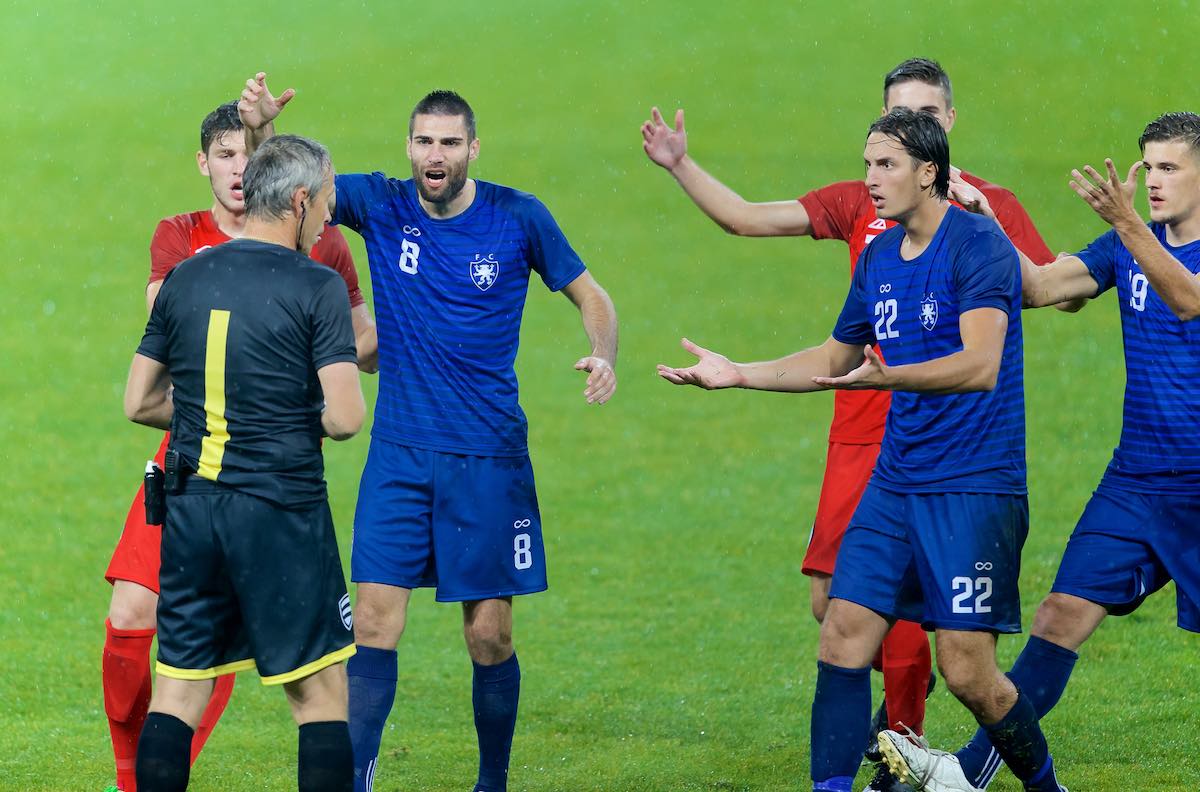 Image of football players arguing with referee