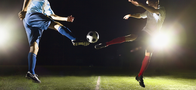 Football players mid air under floodlights