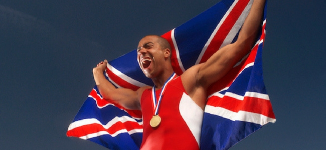 Gold medalist holding a UK flag behind him