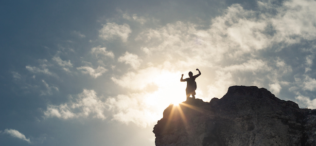 Man celebrating reaching the top of a mountain