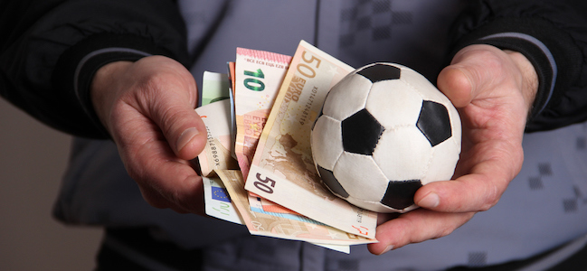 Man holding football and money in his hands