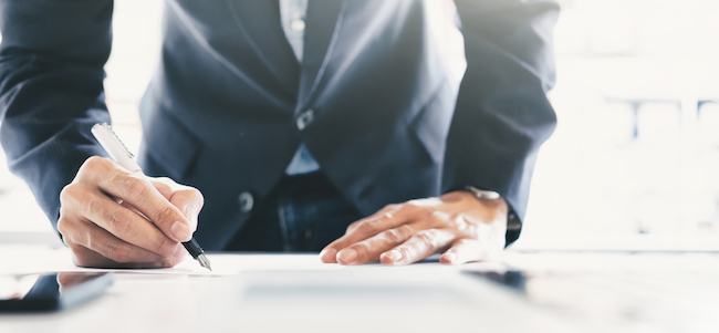 Man signing a contract on top of a table