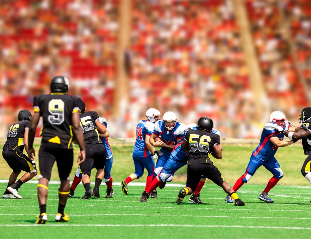 American football running back carrying ball through defenders