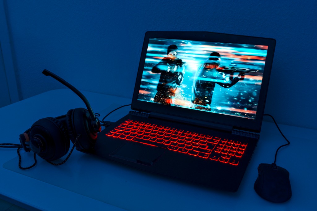 Gaming Laptop With Mouse and Headphones and Image Of A Game With Two Men With Guns On Screen